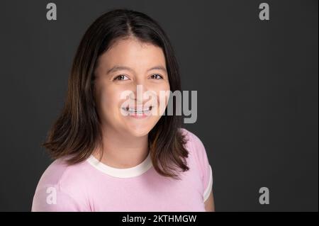 Headshot of young smiling girl with teeth brackets isolated on studio background Stock Photo