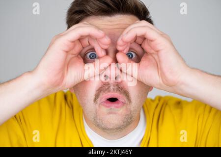 Caucasiann man making binoculars shape with his hands and looking through it  Stock Photo