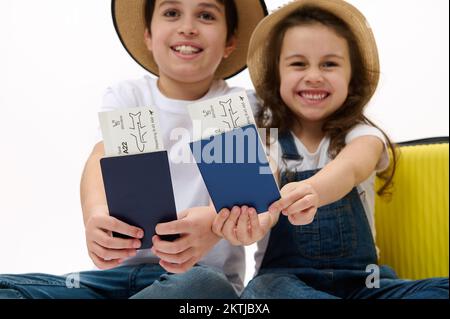 Flight ticket or boarding pass in blurred traveler passenger kid's hands near a yellow suitcase over white background Stock Photo