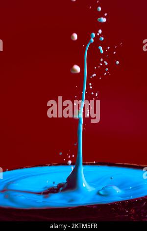 collision of moving water drops of blue color on a purple red background forming figures and waves when falling and colliding with each other photogra Stock Photo