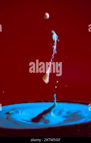 collision of moving water drops of blue color on a purple red background forming figures and waves when falling and colliding with each other photogra Stock Photo