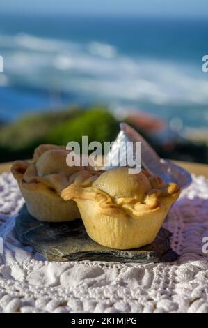 Portugeese food, oven baked chicken pie empada de frango, served outdoor with view on blue sunny Atlantic ocean near Sintra in Lisbon area, Portugal Stock Photo