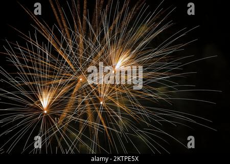 White, gold and yellow fireworks against a black sky background at night. Stock Photo