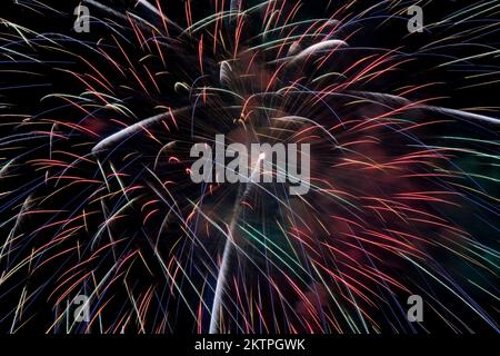 Red, blue and green fireworks against a black sky background at night. Stock Photo