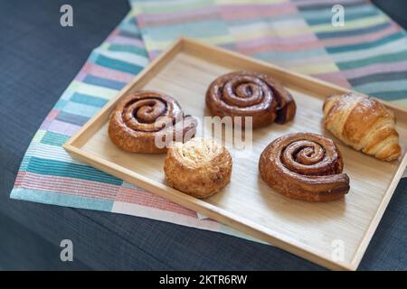 Homemade cinnamon buns with spices and caramel on parchment paper. Stock Photo