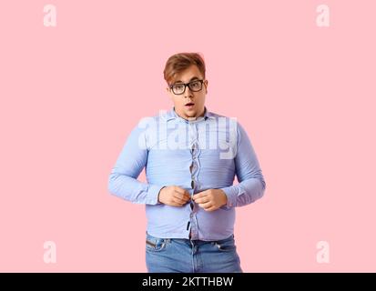 Young overweight man in tight shirt on pink background Stock Photo