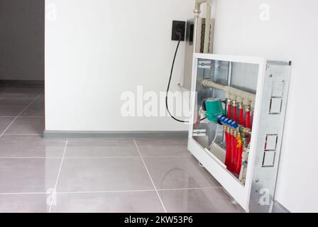 Collector for regulating heating in the house. Closet with faucets and circulation pump for underfloor heating Stock Photo