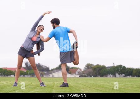 My best workout partner. two people helping each other stretch on a grassy field. Stock Photo