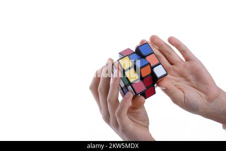 Child holding a Rubik's cube in hand on a white background Stock Photo