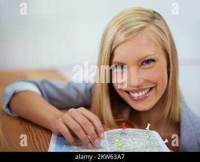 These are all the places Ive been. Cropped portrait a young woman putting pins onto a map. Stock Photo