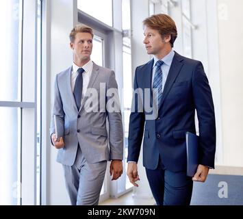 Last minute finalisations before their meeting. A cropped image of two businessmen walking and talking. Stock Photo