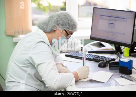 May 31, 2021. Belarus, Gomil, Central Hospital.The doctor at the reception sits at the table and writes something. Stock Photo