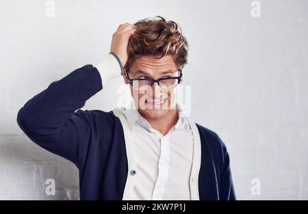 Im confused...A handsome young man looking perplexed as he stands with his hand in his hair. Stock Photo
