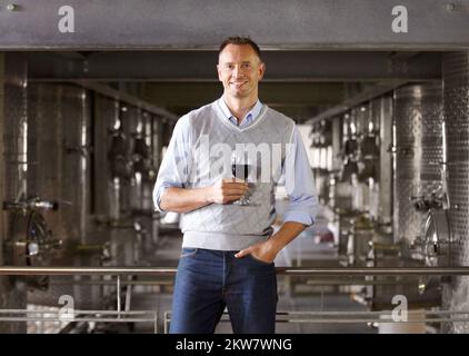 He is the best in his field. Portrait of a mature wine maker with a glass of red wine in his cellar. Stock Photo