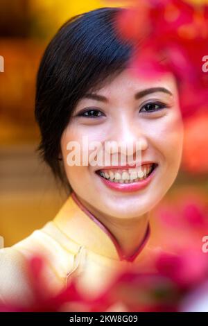 Vietnamese hotel receptionist posing for portrait wearing ao dai, Ho Chi Minh City, Vietnam Stock Photo