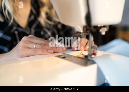 Close up of hands dressmaker scribbling fabric on sewing machine. tailoring at the factory. Copy space Stock Photo