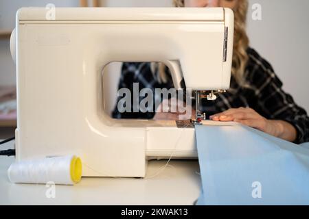 woman sewing clothes while sitting at her workplace in fashion workshop. Copy space Stock Photo