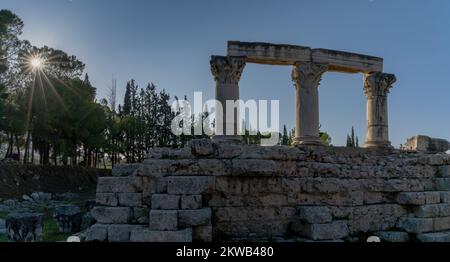 Corinth, Greece - 8 November, 2022: panorama view of the ruins of Ancient Corinth in southern Greece with a sunburst Stock Photo