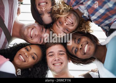 Enjoying campus life. Low angle shot of young university students standing arm in arm on the school campus. Stock Photo