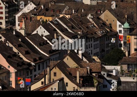 The traffic-free streets of the old town or Altstadt at Schaffhausen, beside the High Rhine in northern Switzerland, are strung with colourful flags or banners displaying the arms and emblems of the Swiss cantons.  The old town retains many fine Gothic, Renaissance and Baroque guild or merchant houses with oriel windows and frescoed facades. Stock Photo