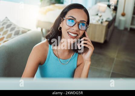 Working from home freelancer talking on phone while doing remote work on computer. Smiling, happy and motivated woman thinking, consulting and Stock Photo