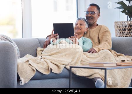 Tablet, relax and movies with a senior couple on the sofa to relaxing while using an online streaming service. Happy, technology and internet with a Stock Photo