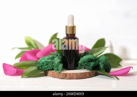 Mock up glass dropper bottle on wooden saw cut podium with rose petals and moss and leaves. beauty cosmetic skin care product Stock Photo