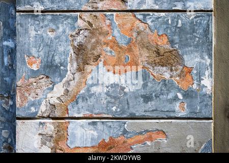 Old decaying plaster on column on wall, stains in pastel color (blue, red, orange and gray), abstract texture background. Stock Photo