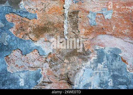 Old decaying plaster on the wall, nice stains in pastel color (blue, red, orange and gray), abstract texture background. Stock Photo