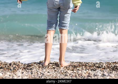 Woman stands on line of sea surf on sunny day. Stock Photo