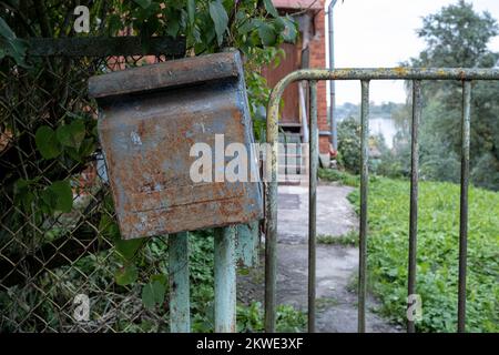 Mailbox is hanging on the fence. Old, rusty mailbox with peeling paint. Stock Photo