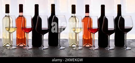 Different wine bottles red, white, rose on concrete background. Beautiful wine variety or assortment concept. Large background for banner Stock Photo