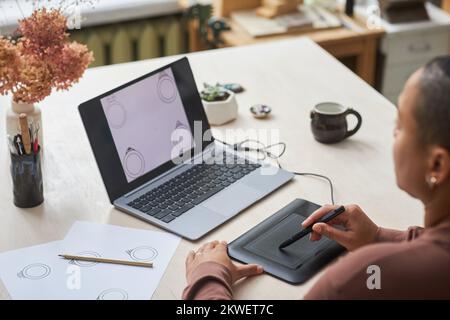 Closeup of female artist using graphic tablet while designing jewelry rings in studio Stock Photo