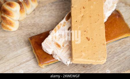 Top view of Three type of  Spanish turron, hard almond, soft almond and burnt egg yolk nougat and marzipan on wooden background. Traditional Christmas Stock Photo