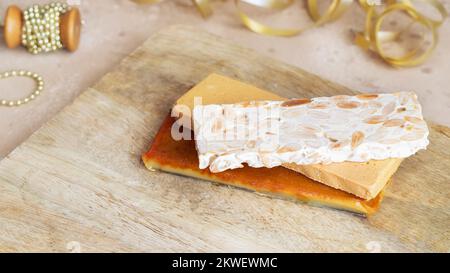 Three type of  Spanish turron, hard almond, soft almond and burnt egg yolk nougat on wooden cut board with Christmas decoration Stock Photo