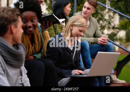 Working on her project. a group students looking at a laptop on campus. Stock Photo