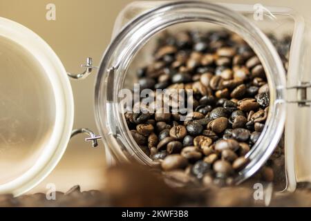 A glass jar full of coffee beans overturned on a table Stock Photo