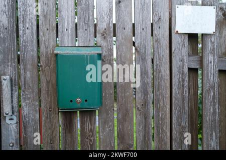 Mailbox, green on a wooden gate, a frame hangs on the fence nearby. Stock Photo