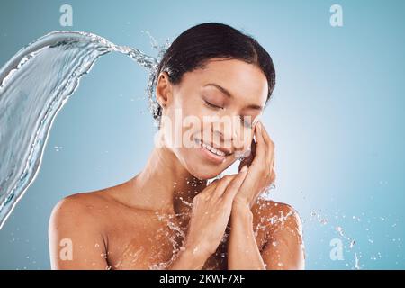 Beauty, water splash and skincare, black woman on blue background in studio. Fashion, health and wellness, clean water shower on woman with healthy Stock Photo