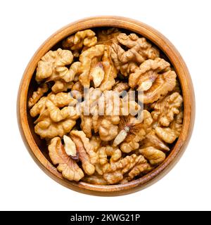 Walnut kernel halves, in a wooden bowl. Shelled, dried seeds of the common walnut tree Juglans regia, used as snack or for baking. Stock Photo