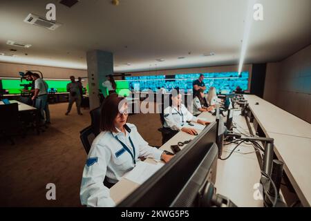 Group of female security operators working in a data system control room Technical Operators Working at workstation with multiple displays, security Stock Photo