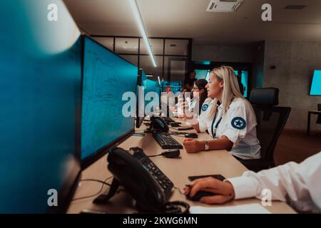 Group of female security operators working in a data system control room Technical Operators Working at workstation with multiple displays, security Stock Photo