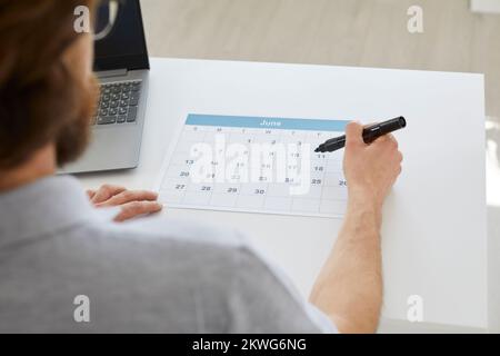 Businessman sitting at his desk and using a calendar to organize his business schedule Stock Photo