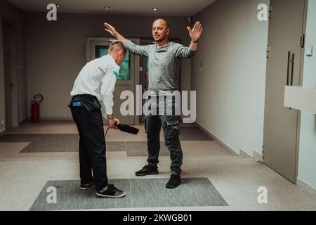 Security guard making body searching procedure on man for finding hidden objects before entering in treasury department Stock Photo