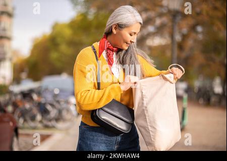 Woman with a papaer bag after shopping in a city street Stock Photo