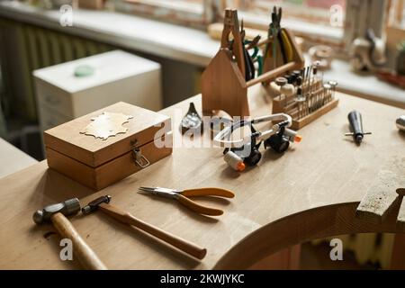 Close up of jewelers workstation with wooden table and various tools in cozy artisanal setting Stock Photo