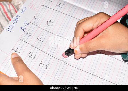 Hand of a Little Girl rubbing out pencil eraser on her school homework book, Pune, Maharashtra, India Stock Photo