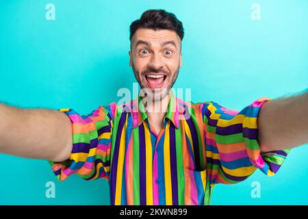 Portrait of positive astonished guy with brunet haircut wear colorful shirt shouting impressed sale isolated on teal color background Stock Photo