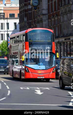 Red double decker bus in traffic on a street in Knightsbridge, London. Stock Photo