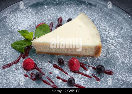 A piece of cheesecake with berries and mint Stock Photo
